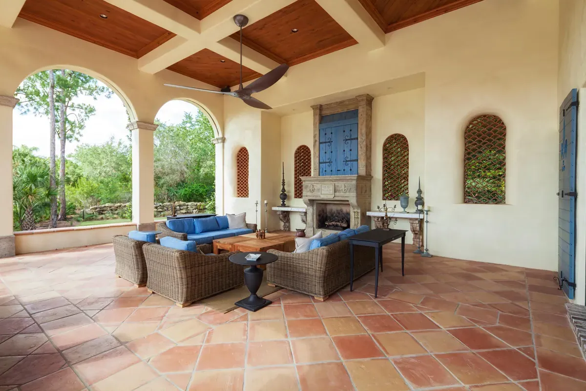Ventilador de techo moderno en una terraza cubierta de estilo hacienda con techo de madera y piso de terracota